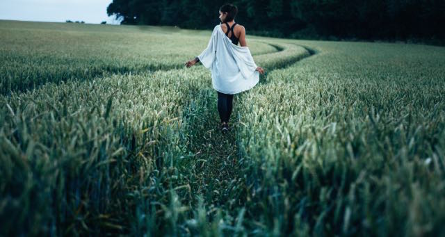 girl in a blue shirt walking in green wheat