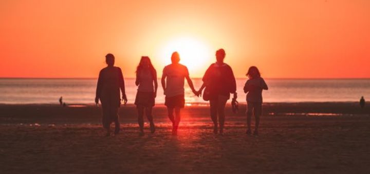 group of people walking on the beach at sundown