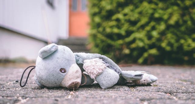 teddy bear on the ground in front of a house