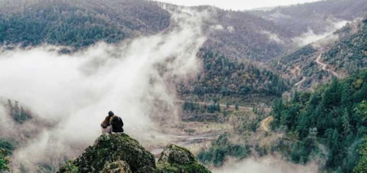 couple sitting on a rock overlooking a foggy valley