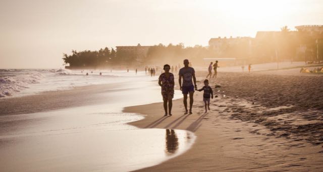 family of three walking on the beach at sunset