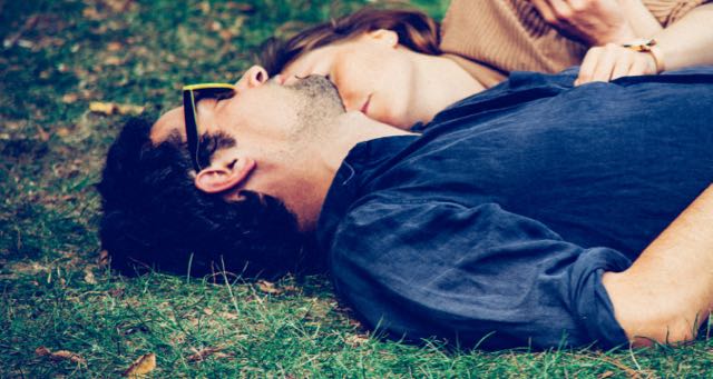 couple laying on the grass in a park