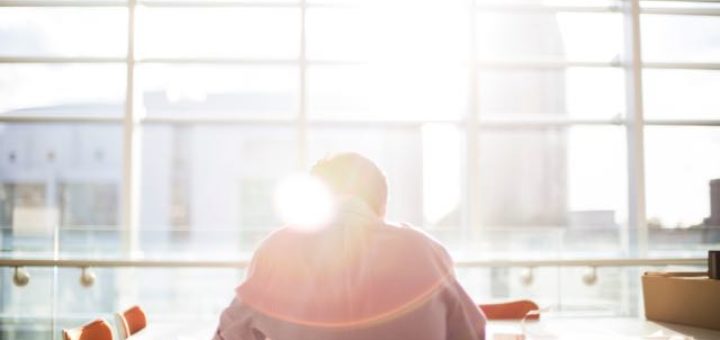 man sitting in conference room overlooking a city