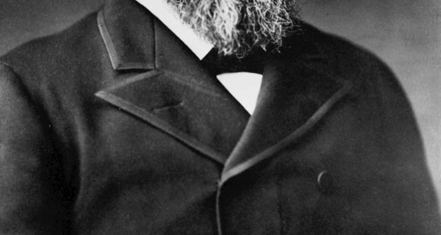 black and white photo of a man with beard in black trench coat