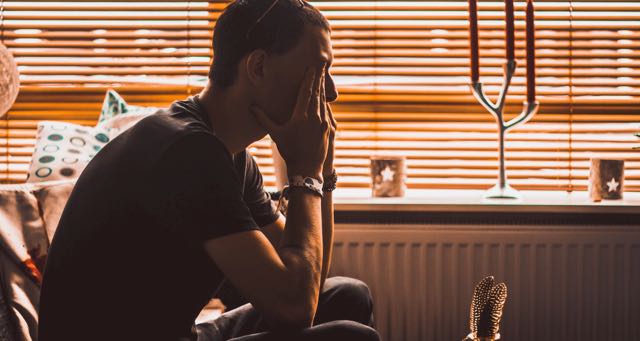 man covering his face with his hands
